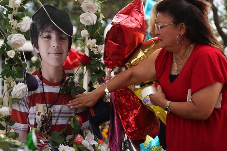 UVALDE, TEXAS - JUNE 01: Yvette Reyes of San Antonio puts a rose on the picture of a shooting victim at a memorial outside Robb Elementary School June 1, 2022 in Uvalde, Texas. Nineteen students and two teachers were killed on May 24 after an 18-year-old gunman opened fire inside the school. Wakes and funerals for the 21 victims are scheduled throughout the week.  (Photo by Alex Wong/Getty Images)