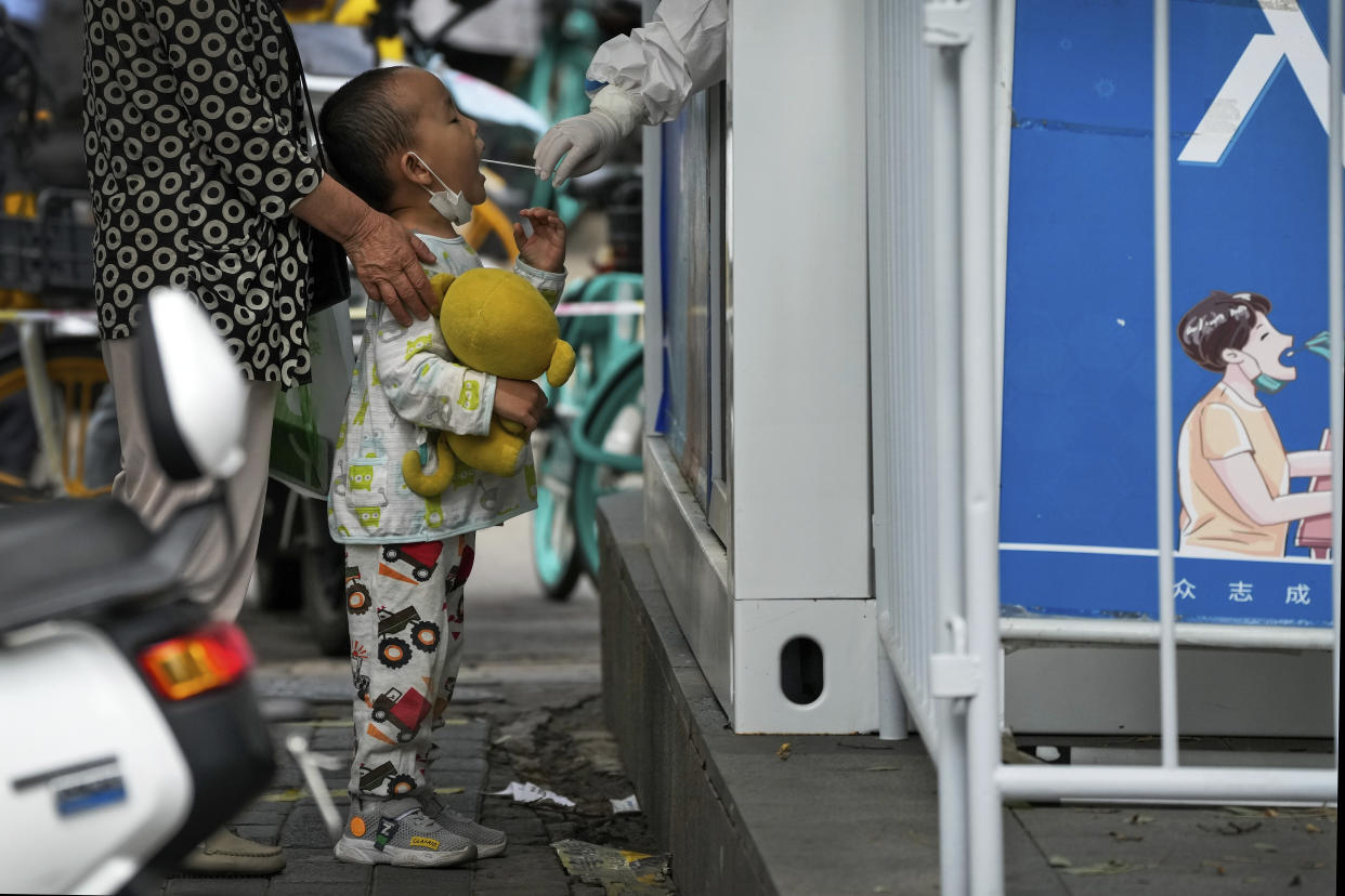 A child holding a soft toy gets a throat swab at a COVID-19 testing facility in Beijing, Monday, June 13, 2022. China's capital has put school online in one of its major districts amid a new COVID-19 outbreak linked to a nightclub, while life has yet to return to normal in Shanghai despite the lifting of a more than two month-long lockdown. (AP Photo/Andy Wong)