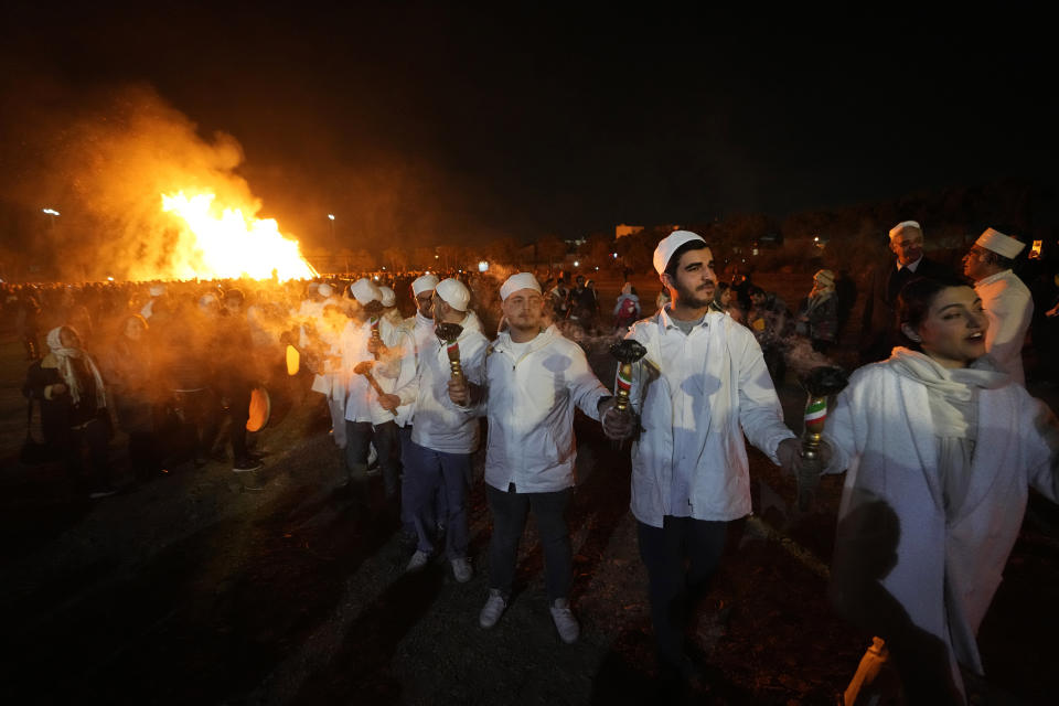 Iranian Zoroastrian youth join hands after setting a prepared pile of wood on fire as they celebrate their ancient mid-winter Sadeh festival in the outskirts of Tehran, Iran, Tuesday, Jan. 30, 2024. Hundreds of Zoroastrian minorities gathered after sunset to mark their ancient feast, creation of fire, dating back to Iran's pre-Islamic past. (AP Photo/Vahid Salemi)