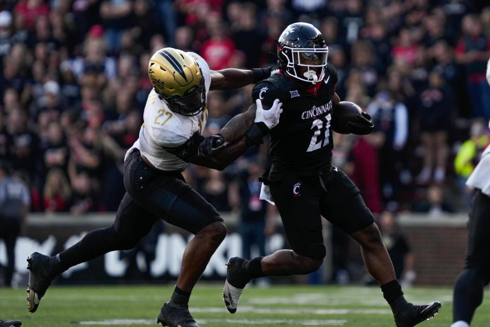 UC's running back Corey Kiner (21) pushes through UCF's defense at Nippert Stadium on Saturday November 4, 2023. Kiner had 113 yards rushing and teammate Ryan Montgomery added 114 in the 28-26 loss.