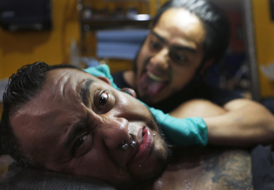 In this April 18, 2019 photo, tattoo artist Lalo Calva inks a tattoo on client Adrian Alonso Rodriguez, a journalist, announcer and dubbing artist, at the Corona Tattoo parlor in Mexico City. Not only inks and techniques have changed in Mexico over the years, but tattoos themselves have evolved from stigmatized symbols of gangs, violence and poverty to an art form. (AP Photo/Marco Ugarte)