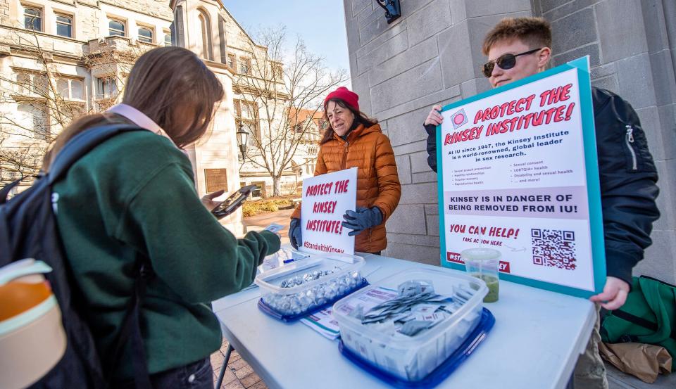 Indiana University graduate student Rory Barro, right, and Jennifer Bass, middle, hand out free condoms at the Sample Gates in support of the Kinsey Institute last week.