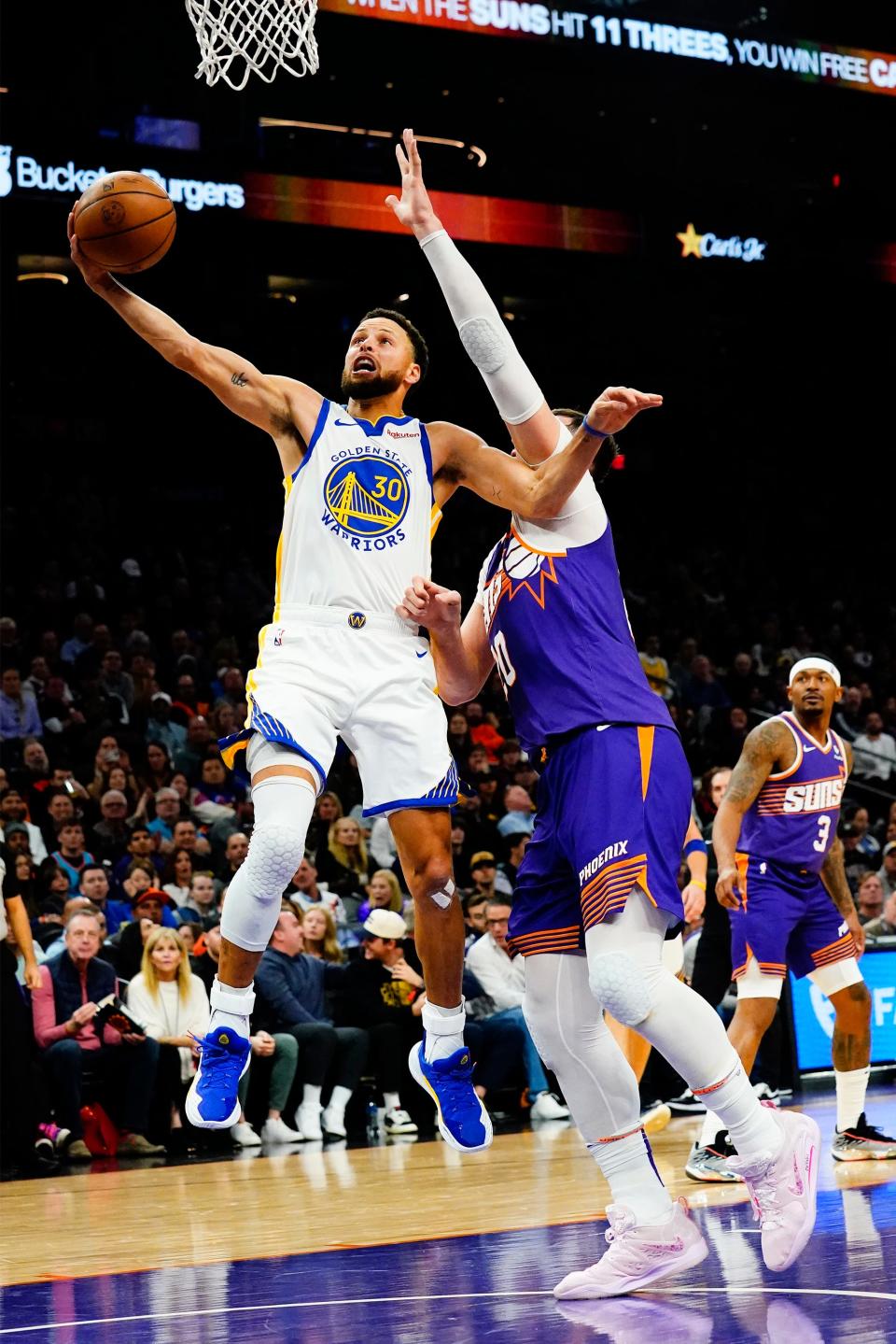 Golden State Warriors guard Stephen Curry (30) scores past Phoenix Suns center Jusuf Nurkic (20) in the first half at Footprint Center in Phoenix on Dec. 12, 2023.