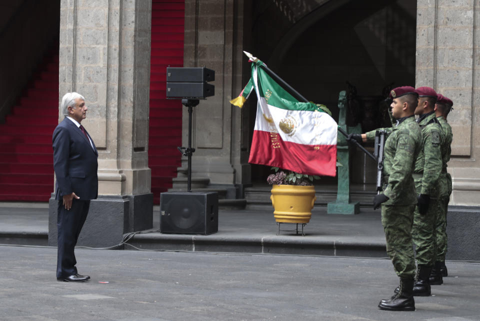 Mexican President Andres Manuel Lopez Obrador salutes the flag after speaking at the National Palace in Mexico City, Sunday, April 5, 2020. Mexico's Treasury reduced its forecast for the year this week to a contraction of the Mexican economy, which was already in a technical recession. López Obrador, however, has labeled the situation a "transitory crisis" and says things will be good again soon. (AP Photo/Eduardo Verdugo)