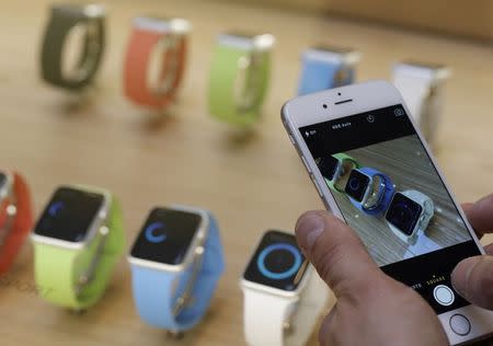 A customer uses his iPhone to take pictures of the new Apple Watch displayed at an Apple Store in Paris April 10, 2015. REUTERS/Christian Hartmann