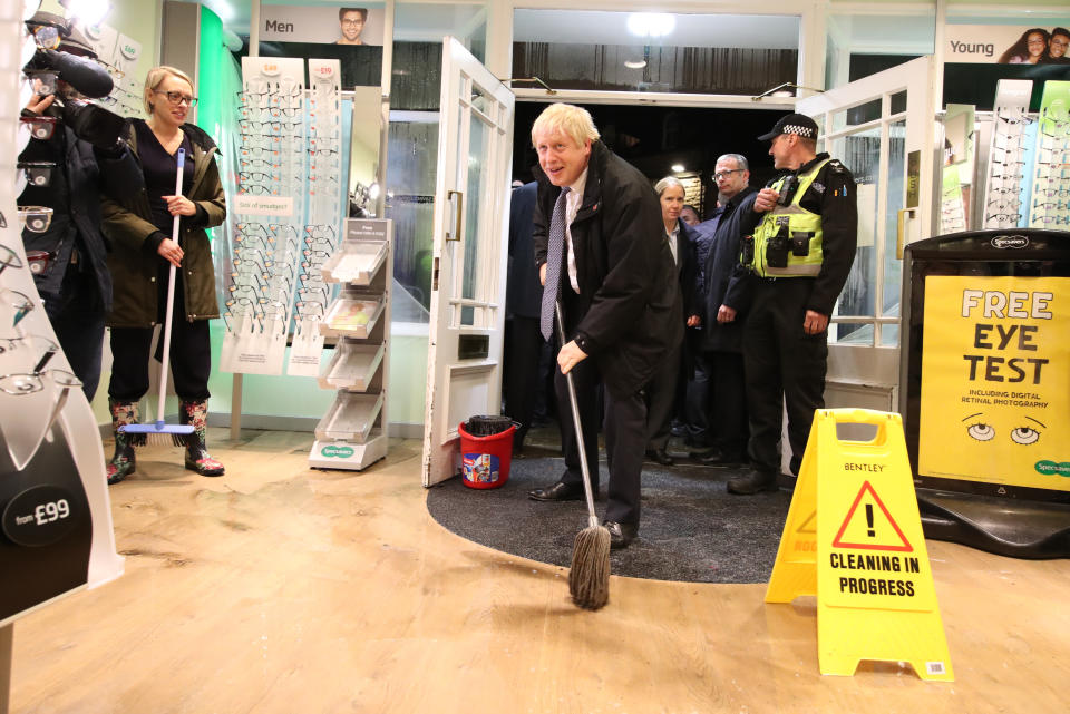 Prime Minister Boris Johnson helps with the clean up at an opticians as he visits Matlock, Derbyshire to view the flooding.