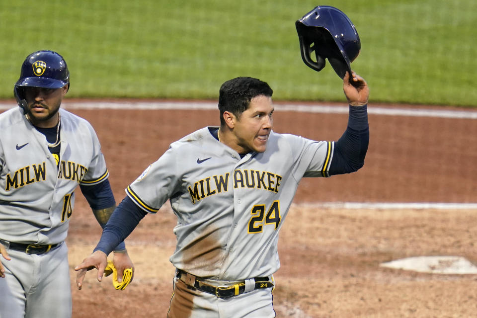 Milwaukee Brewers' Avisail Garcia (24) and Omar Narvaez, left, return to the dugout after scoring on a double by Lorenzo Cain off Pittsburgh Pirates starting pitcher Max Kranick during the fourth inning of a baseball game in Pittsburgh, Wednesday, July 28, 2021. (AP Photo/Gene J. Puskar)