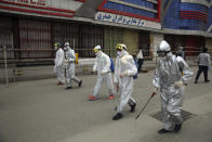 Volunteers in protective suits spray disinfectant on storefronts to help curb the spread of the coronavirus in Kabul, Afghanistan, Sunday, March 29, 2020. The government Friday ordered a three-week lock-down for Kabul to stem the spread of the new coronavirus. (AP Photo/Rahmat Gul)