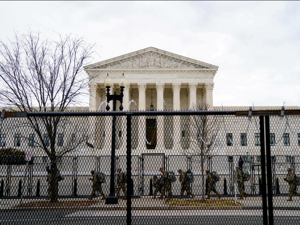 <p>National Guard troops walk behind fencing in front of the US Supreme Court as security tightens ahead of presidential inaugural events on Capitol Hill in Washington, DC</p> ((Reuters))