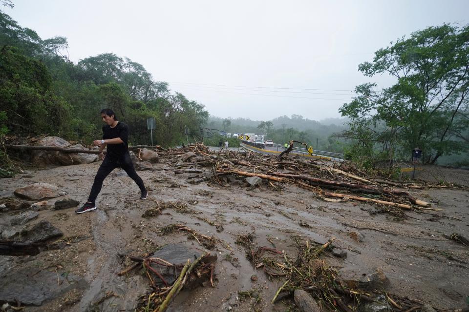 A man crosses a highway blocked by a landslide triggered by Hurricane Otis near Acapulco, Mexico, on Oct. 25.