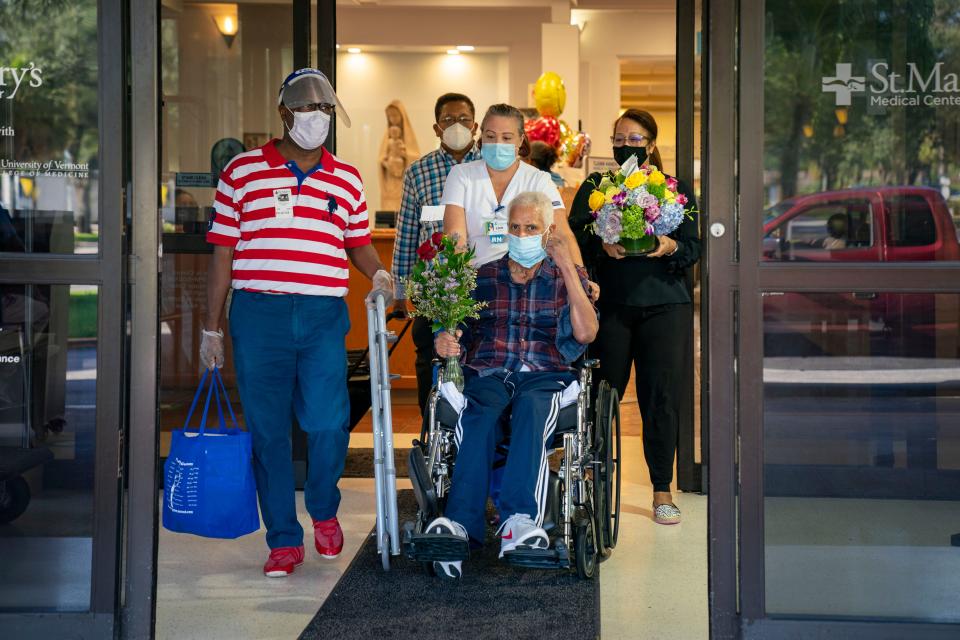 Dr. Vladimir Laroche, 68, who spent 87 days on a ventilator during his battle with the deadly coronavirus was released from the hospital's rehabilitation program at St. Mary's Medical Center surrounded by (l to r) Paul Leroche, Henry Augustin, Erin Correa, RN, and Sandra Elivert on July 24, 2020 in West Palm Beach, Florida. [GREG LOVETT/palmbeachpost.com]