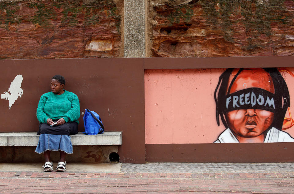 A woman sits next to murals for the removal of President Zuma in Johannesburg