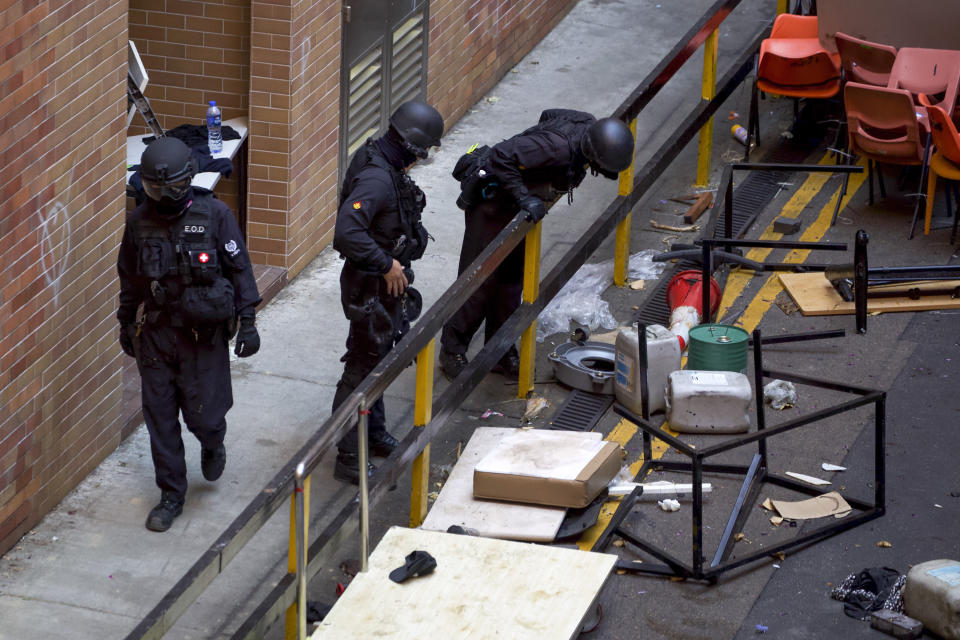 Policemen from Explosive Ordnance Disposal (EOD) unit search for dangerous materials at the Hong Kong Polytechnic University campus in Hong Kong, Thursday, Nov. 28, 2019. Police safety teams Thursday began clearing a university that was a flashpoint for clashes with protesters, and an officer said any holdouts still hiding inside would not be immediately arrested. (AP Photo/Ng Han Guan)