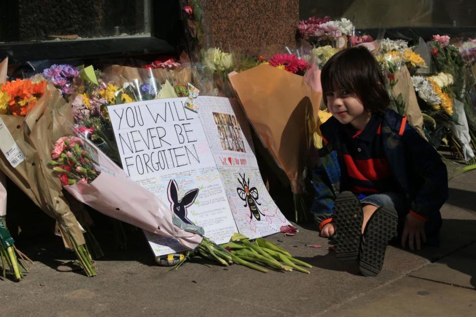 Grieving: A young boy sits next to messages and flowers left in Manchester (PA)