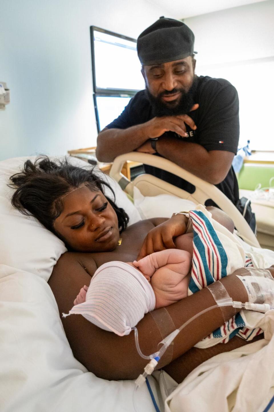 A mother holds her baby as the father looks on.