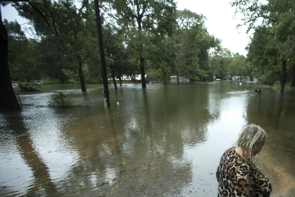 Linda Anson stands at the edge of her flooded neighborhood inundated by rains from Tropical Depression Imelda on Thursday, Sept. 19, 2019, in Spendora, Texas. Her house, where she has lived for just two weeks, is the one with the white roof. (Brett Coomer/Houston Chronicle via AP)