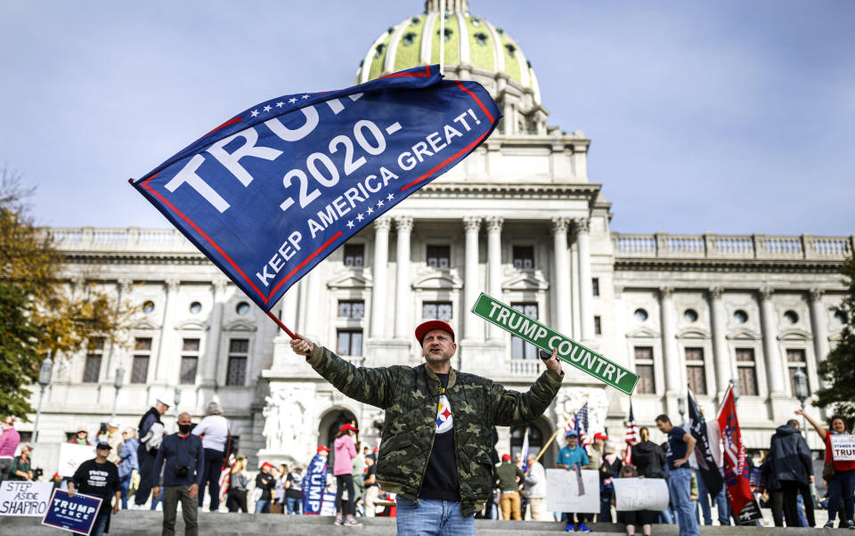 A man waves a flag at a pro-Trump rally at the Pennsylvania state Capitol in Harrisburg, Pa., Friday, Nov. 5, 2020. (Dan Gleiter/The Patriot-News via AP)