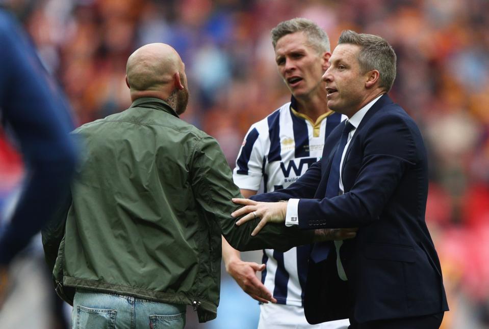 Millwall boss Neil Harris asks a fan to leave the pitch as angry Steve Morison looks on