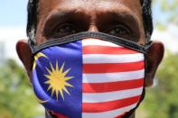 A supporter of People's Justice Party wearing Malaysia's flag mask pose for a picture outside National Palace, Kuala Lumpur