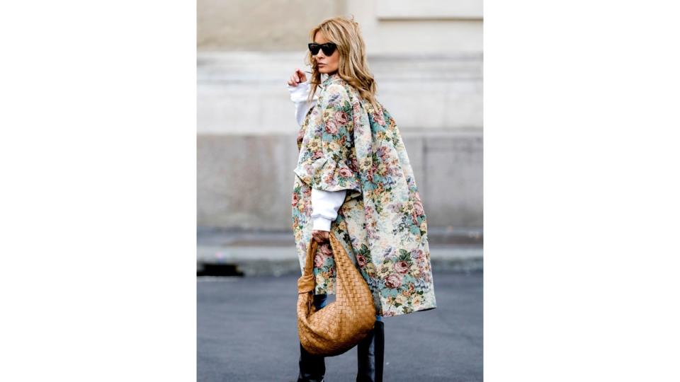 Influencer Gitta Banko, wearing a brokat coat with floral print by Celin, a Jeans by Jeans AG, black knee boots by Isabel Marant, a creme colored oversize sweater woth shoulder pads by Zara, a camel colored jodie bag by Bottega Veneta and sunglasses by Bottega Veneta, is seen during the Milan Women's Fashion Week on September 26, 2020 in Milan