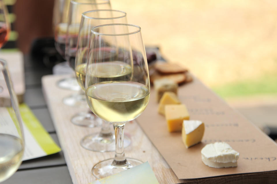 Wine glasses with white wine, paired with assorted cheeses on a wooden table