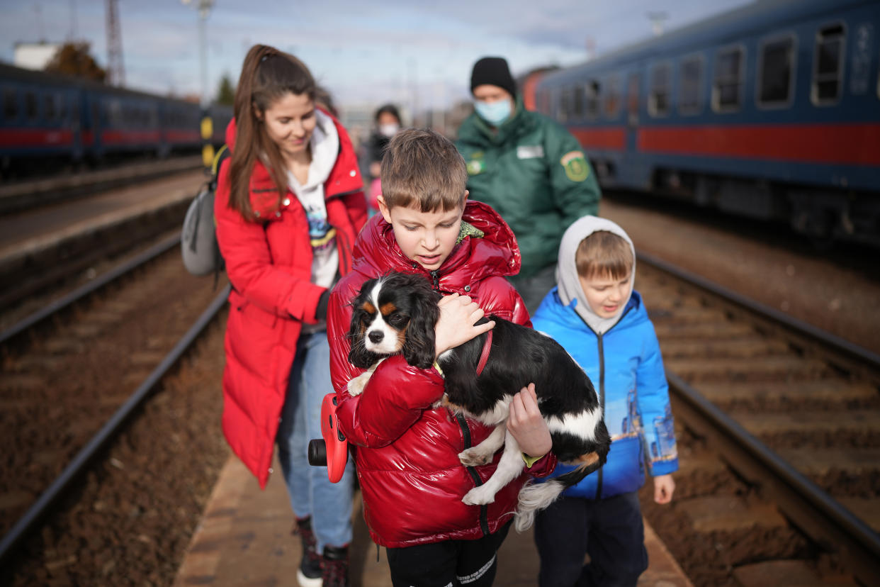 Kyryl, 9, holds his dog in his arms while walking with his family along train tracks. 