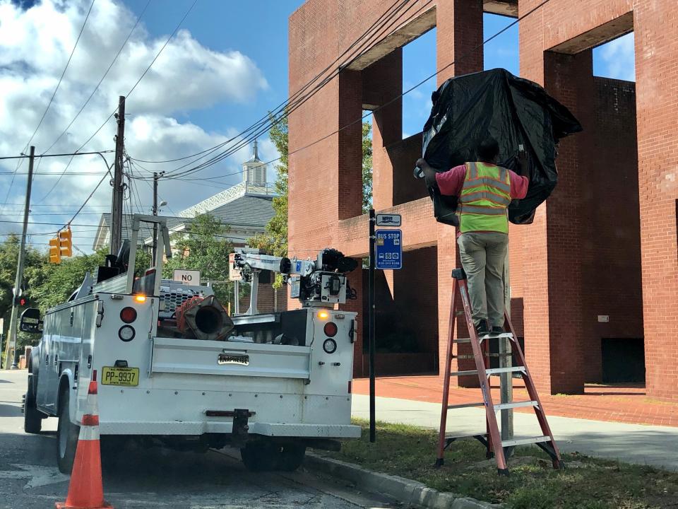 In this Oct. 28, 2019, photo, a worker with the North Carolina Department of Transportation covers the 1898 Wilmington coup highway historic marker that will be unveiled at a ceremony, in Wilmington, N.C. The marker commemorates the violent overthrow by white Democrats of the fusion government of legitimately elected blacks and white Republicans in Wilmington. The Democrats burned and killed their way to power in what's viewed as a flashpoint for the Jim Crow era of segregation and the only successful coup d'etat in American history. (Hunter Ingram/The Star-News via AP)