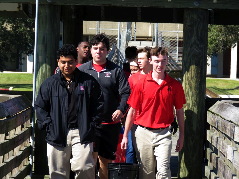 Oyster garden interns Colin Wood, left, and Dylan McShane, seniors at St. Stanislaus HIgh School's pier in Bay St. Louis, Miss., head down the school's pier toward the oyster garden on Monday, Nov. 15, 2021. Behind them are seniors taking Marine Biology II. The school is among more than 50 locations -- most of them private docks -- and more than 1,000 nationwide where volunteers raise oysters to help restore reefs. (AP Photo/Janet McConnaughey)