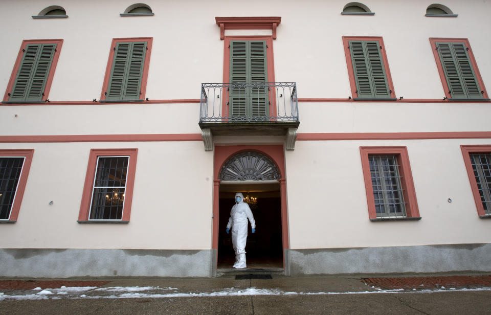 Doctor Luigi Cavanna stands at the entrance of a building as he waits for his assistant nurse Gabriele Cremona prior to visiting a COVID-19 patient in his home, in Caorso, near Piacenza, Italy, Wednesday, Dec. 2, 2020. (AP Photo/Antonio Calanni)