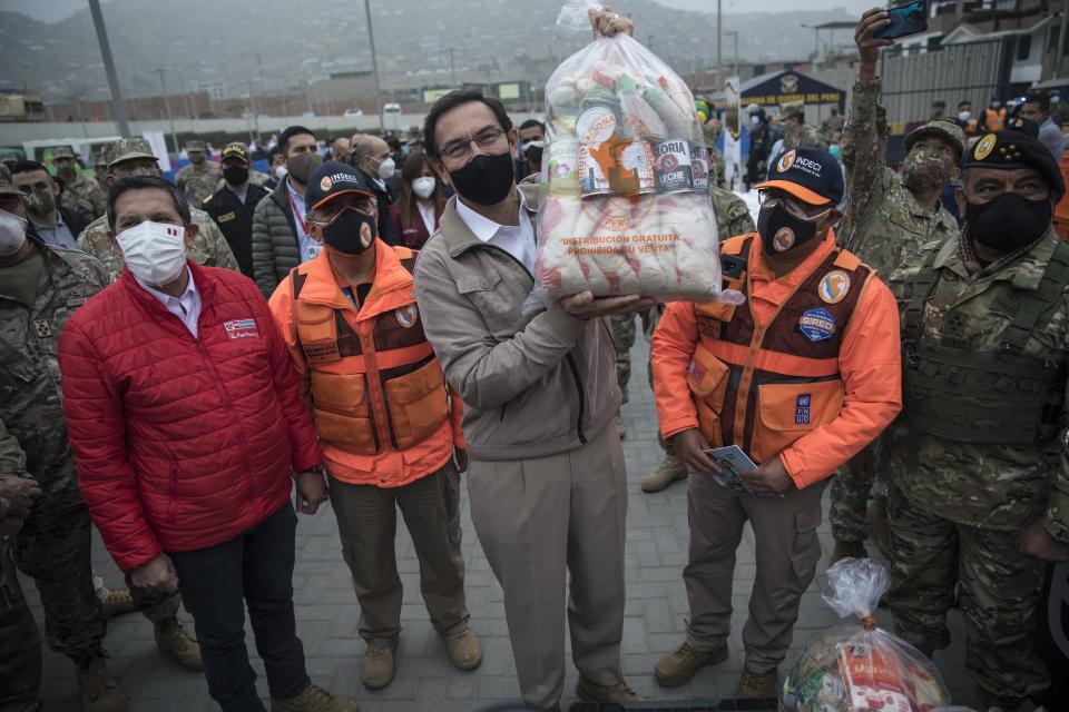 El presidente peruano Martín Vizcarra le muestra a la prensa una de varias bolsas de comida que serán distribuidas a hogares en situación de pobreza en Villa el Salvador, a las afueras de Lima, Perú el martes 15 de septiembre de 2020. (AP Foto/Rodrigo Abd)