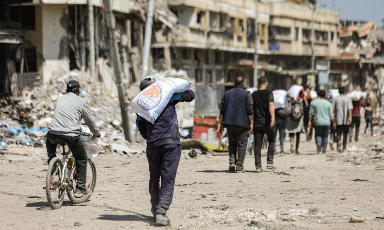 <span>Palestinians receive a bag of flour from an aid truck in the north of Gaza City. Dr Selina Namchee Lo of the Australian Global Health Alliance says it is ‘unconscionable’ to withhold access to food for those who need it.</span><span>Photograph: Anadolu/Getty Images</span>