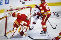 Ottawa Senators' Austin Watson, center, is checked by Calgary Flames' Nikita Nesterov, right, into Flames goalie Jacob Markstrom during second-period NHL hockey game action in Calgary, Alberta, Sunday, March 7, 2021. (Jeff McIntosh/The Canadian Press via AP)