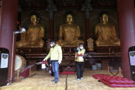 Residents of Jongno-Gu wearing face masks spray disinfectant as a precaution against the coronavirus at the Jogyesa Buddhist temple in Seoul, South Korea, Thursday, Feb. 27, 2020. South Korea and China each reported hundreds more virus cases Thursday as the new illness persists in the worst-hit areas and spreads beyond borders. (AP Photo/Ahn Young-joon)