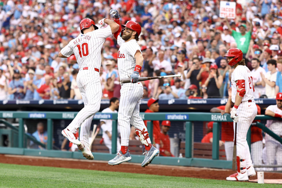 PHILADELPHIA, PENNSYLVANIA - MAY 22: JT Realmuto #10 and Bryce Harper #3 of the Philadelphia Phillies react after a solo home run by Realmuto during the third inning against the Texas Rangers at Citizens Bank Park on May 22, 2024 in Philadelphia, Pennsylvania.  (Photo by Tim Nwachukwu/Getty Images)