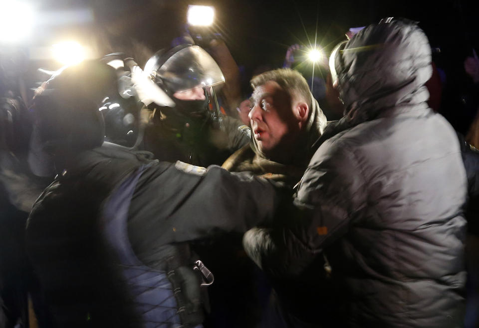 Ukrainian riot police detain a protester, who planned to stop buses carrying passengers evacuated from the Chinese city of Wuhan, outside Novi Sarzhany, Ukraine, Thursday, Feb. 20, 2020. Several hundred residents in Ukraine's Poltava region protested to stop officials from quarantining the evacuees in their village because they feared becoming infected. Demonstrators put up road blocks and burned tires, while Ukrainian media reported that there were clashes with police, and more than 10 people were detained. (AP Photo/Efrem Lukatsky)