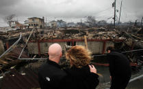 <p>Robert Connolly, left, embraces his wife Laura as they survey the remains of the home owned by her parents that burned to the ground in the Breezy Point section of New York, Tuesday, Oct. 30, 2012. More than 50 homes were destroyed in the fire which swept through the oceanfront community during superstorm Sandy. At right is their son, Kyle. (AP Photo/Mark Lennihan) </p>