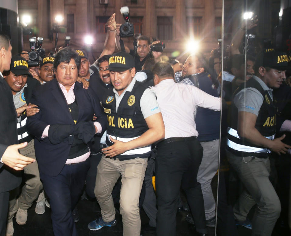 In this photo provided by Peru's Justice Palace press office, Peru's Football Federation President Edwin Oviedo is lead to jail in handcuffs in Lima, Peru, Thursday, Dec. 6, 2018. Oviedo, who was arrested a few months after leading his country back to the World Cup for the first time in 36 years, will be held initially for 15 days as prosecutors investigate his alleged connections to a criminal network that paid for several judges to attend the World Cup in Russia. (Francisco Medina/Peru's Justice Palace via AP)