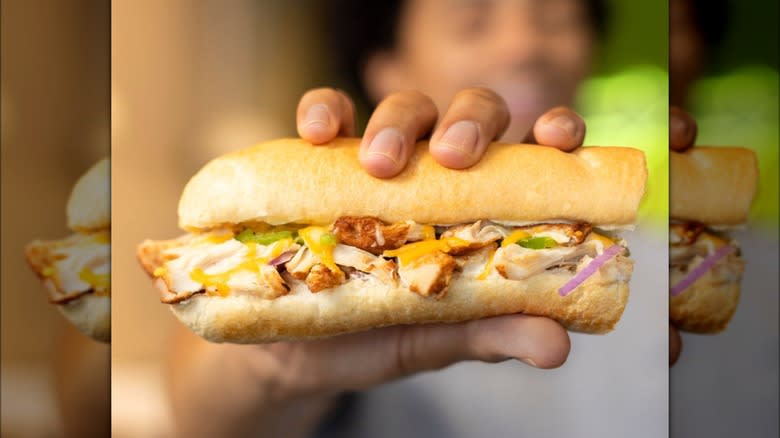 Hand holding a Subway sandwich
