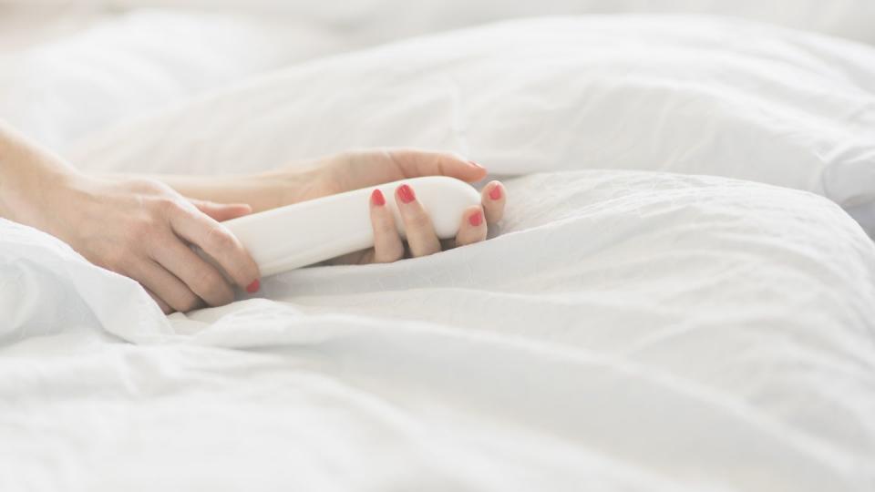 hand of woman holding sex toy in bed