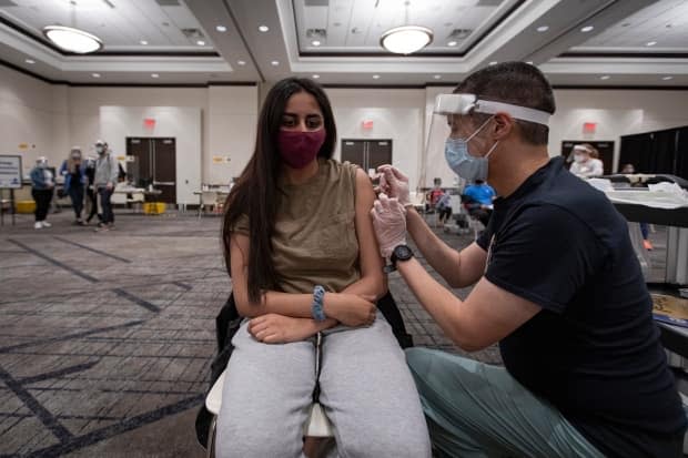 A 19-year-old woman gets her first dose of a COVID-19 vaccine in Mississauga, Ont. Vaccine eligibility expands to Ottawans 18 years and older starting Tuesday morning at 8 a.m. (Evan Mitsui/CBC - image credit)