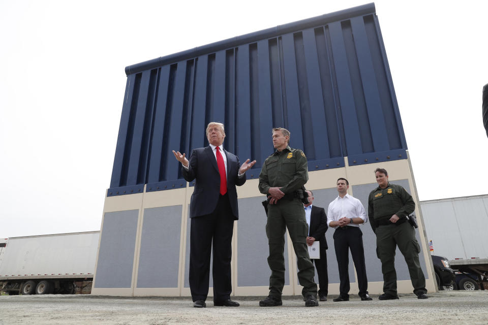 President Donald Trump stands with a Customs and Border Protection agent in front of a border wall prototype while visiting San Diego last month. (Photo: Kevin Lamarque / Reuters)