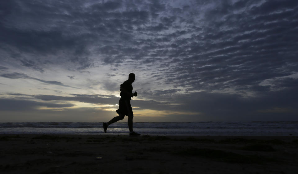 A man runs along the beach at sunrise, Monday, July 27, 2020, in South Padre Island, Texas. Hurricane Hanna passed through the area leaving heavy rains but has been downgraded to a tropical storm as it moves into Mexico. (AP Photo/Eric Gay)