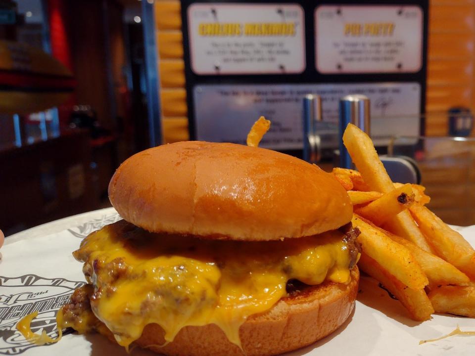 Shot of a burger dripping with melted cheese.