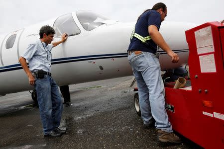 Pilot Nicolas Veloz (L) looks at a worker making adjustments to an airplane before takeoff at Charallave airport outside Caracas September 15, 2014. REUTERS/Carlos Garcia Rawlins