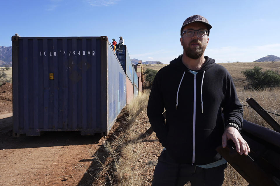 Russ McSpadden, Southwest conservation advocate at the Center for Biological Diversity, stands at the border where shipping containers create a wall between the United States and Mexico in San Rafael Valley, Ariz., Thursday, Dec. 8, 2022. Work crews are steadily erecting hundreds of double-stacked shipping containers along the rugged east end of Arizona’s boundary with Mexico as Republican Gov. Doug Ducey makes a bold show of border enforcement even as he prepares to step aside next month for Democratic Governor-elect Katie Hobbs. (AP Photo/Ross D. Franklin)