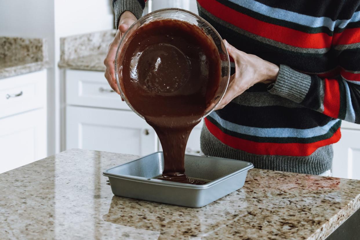 man pours chocolate batter into baking pan