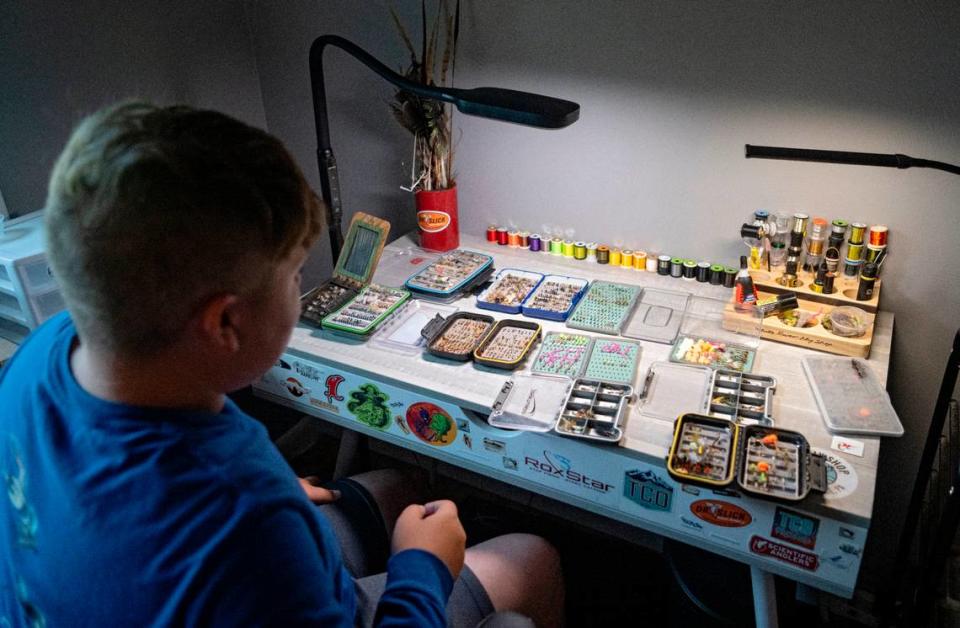 Landis Samples, 12, looks through the tackle boxes full of fly fishing flies he has made.