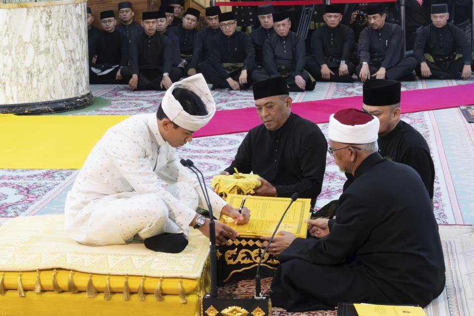 This handout pictures taken by Brunei's Information Department on January 11, 2024 and released on January 12, 2024 shows Brunei's Prince Abdul Mateen, left, signing documents after his solemnization at Sultan Omar Ali Saifuddien Mosque in Bandar Seri Begawan, Brunei. (Brunei's Information Department via AP)