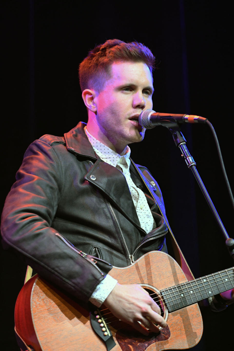 Trent singing and playing guitar on stage