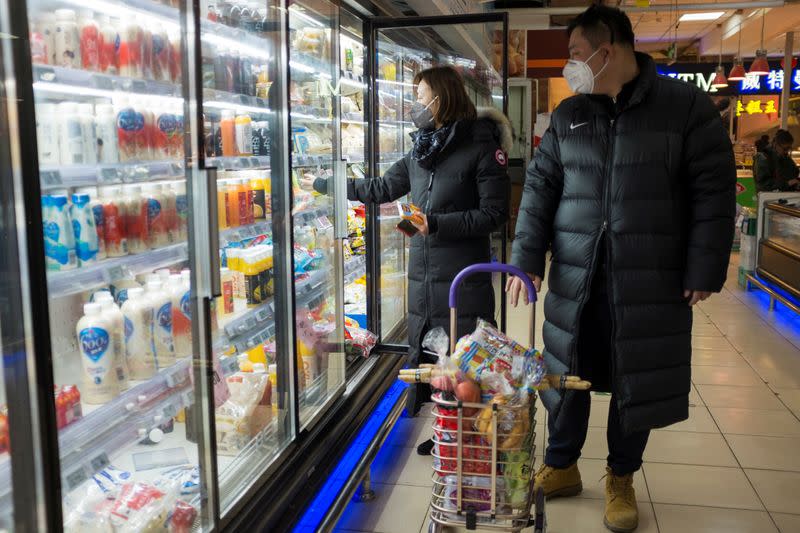 People wear face masks as they select products in a supermarket in Beijing